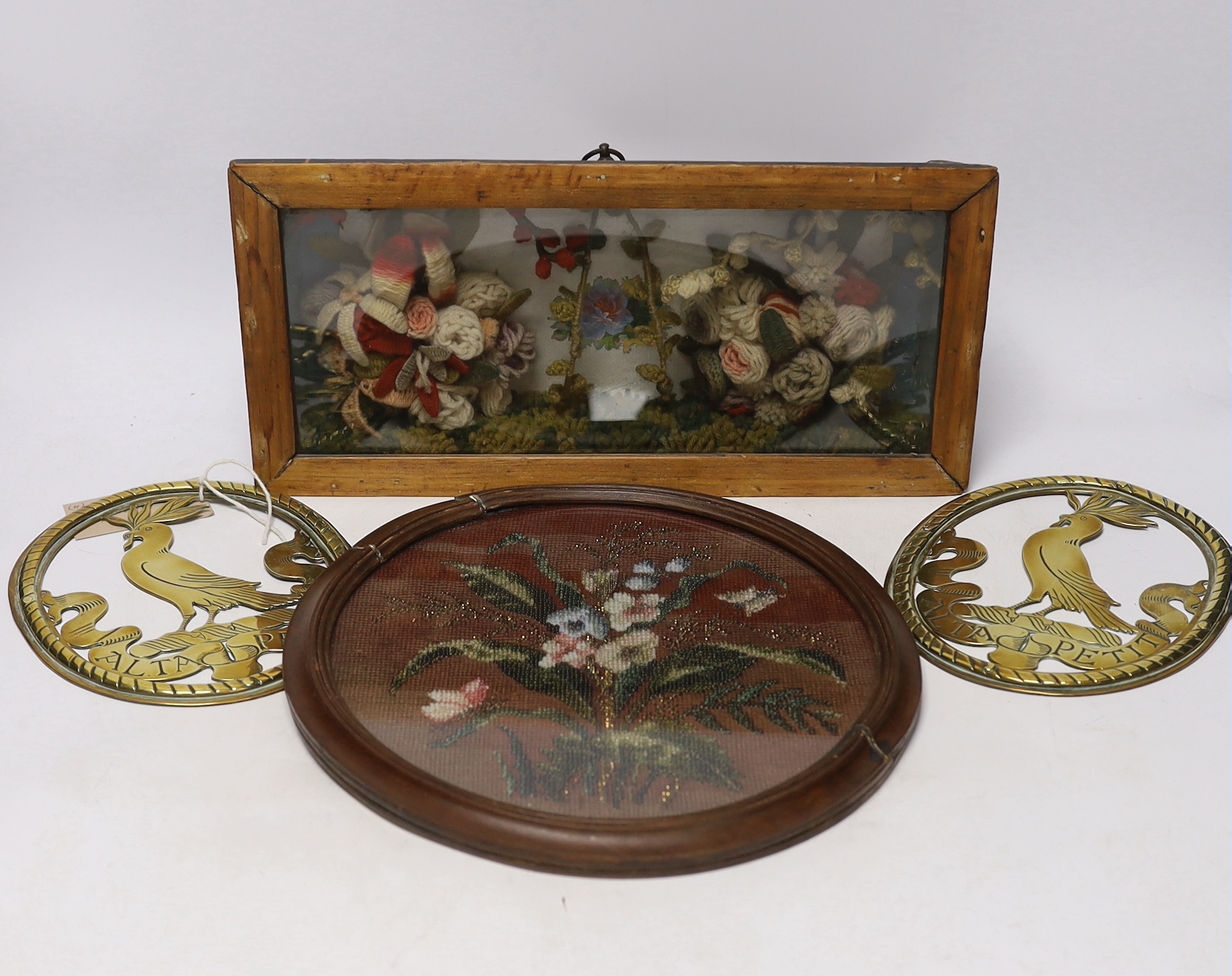 A pair of oval brass crests, a circular framed Berlin beadwork panel and a framed floral wool work diorama, diorama 3.5cm wide x 18cm high